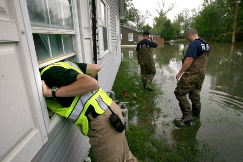 Poplar Bluff police detective Corey Mitchell, left, calls for an elderly woman, who was reported to be trapped in her home in the flood waters.