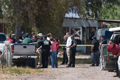 Police investigators comb over a farm property near Wellton, Ariz.