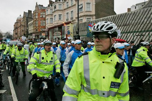 British police officers escort an Olympic torch bearer, as she runs in central London in 2008.