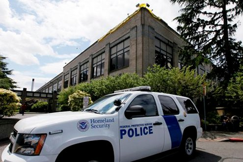 A police vehicle is parked outside a federal building that houses the Seattle Military Processing Center.