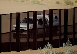 A border patrol vehicle drives along the U.S.-Mexico border fence near Yuma, Ariz.