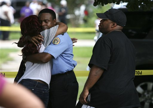 A New Orleans police officer comforts unidentified family members outside the home.