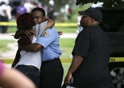 A New Orleans police officer comforts unidentified family members outside the home. A New Orleans police officer comforts unidentified family members outside the home.