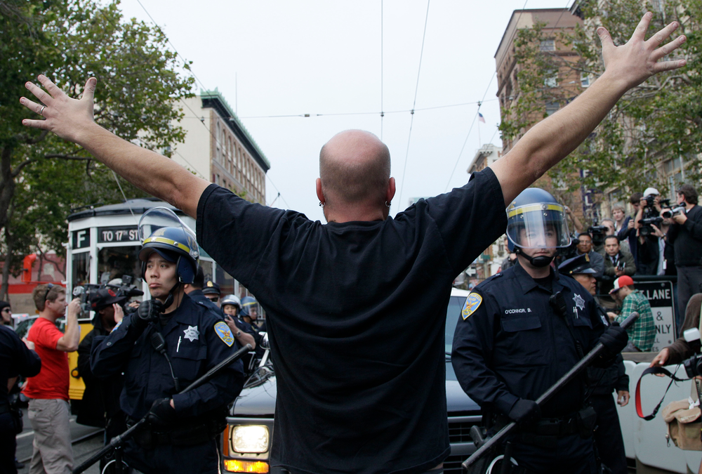 A protester stands in front of San Francisco Police officers before being arrested on Market Street.