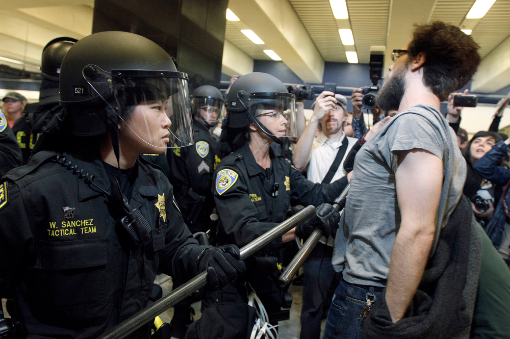 BART police officers push back a protester at the Civic Center station in San Francisco.