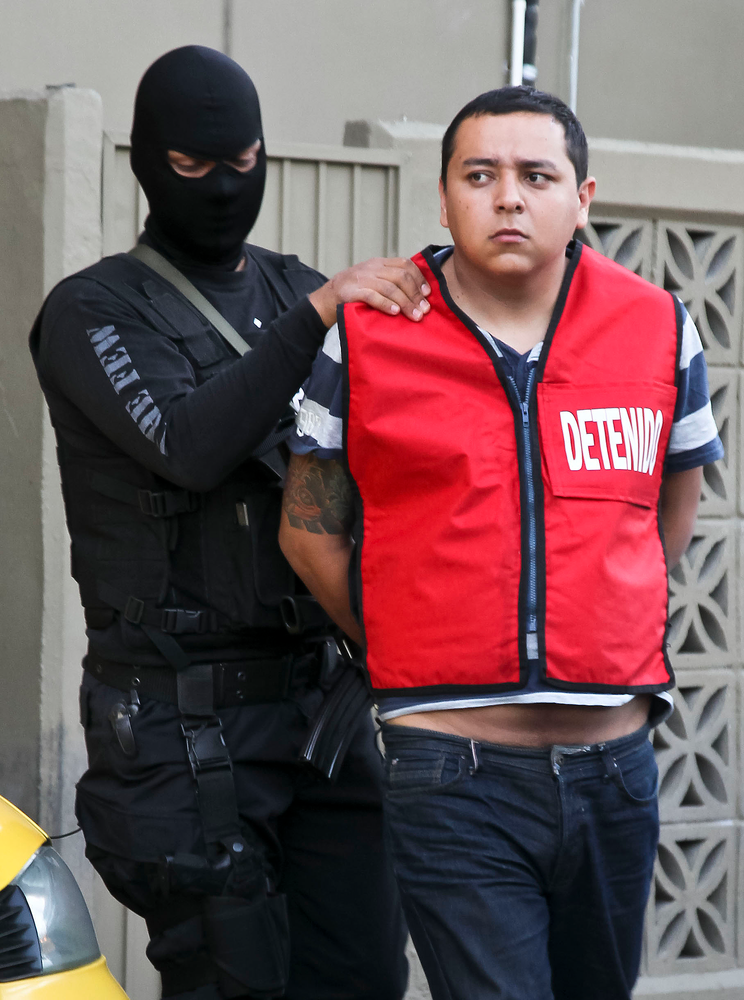 A police officer escorts Javier Martinez, an alleged member of the Zetas drug cartel.