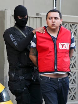A police officer escorts Javier Martinez, an alleged member of the Zetas drug cartel. A police officer escorts Javier Martinez, an alleged member of the Zetas drug cartel.