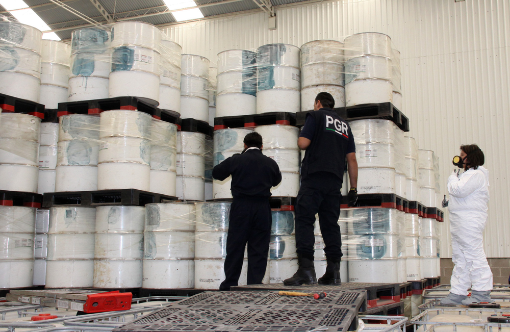 Police investigators look at drums of precursor chemicals for methamphetamine that were seized.