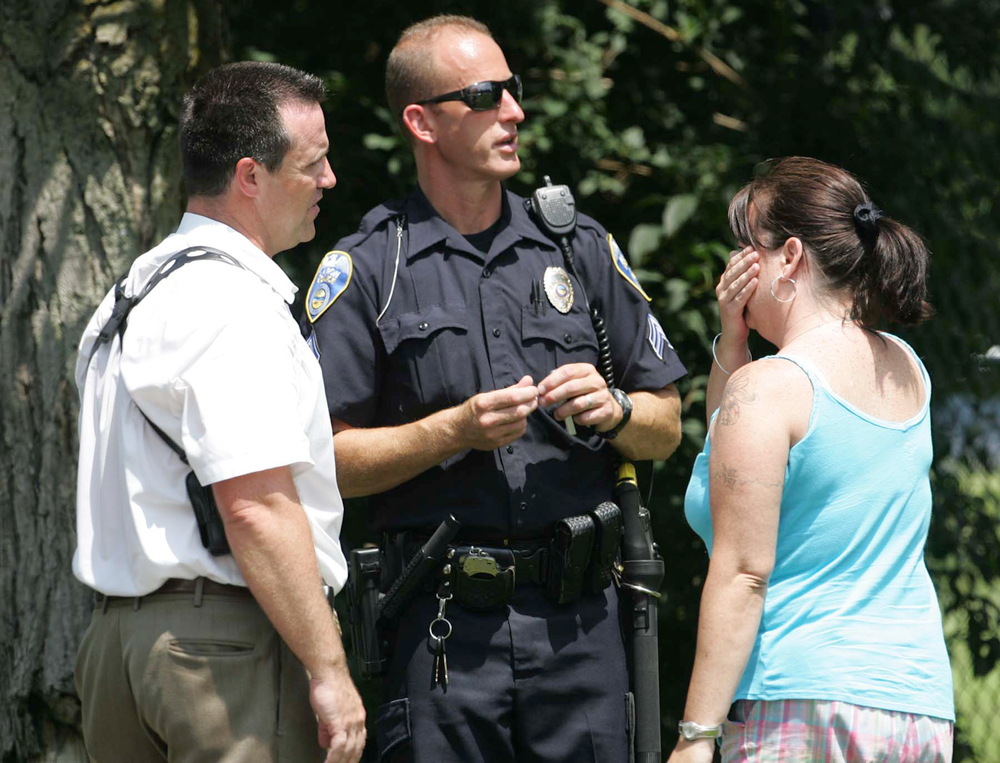 Members of the Akron Police Department talk to an unidentified woman claiming to be a relative at the scene of the shooting.