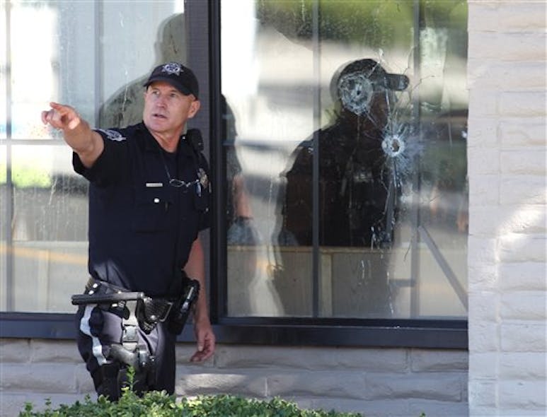With bullet holes seen in a window, officers look for evidence at the scene of the shooting.