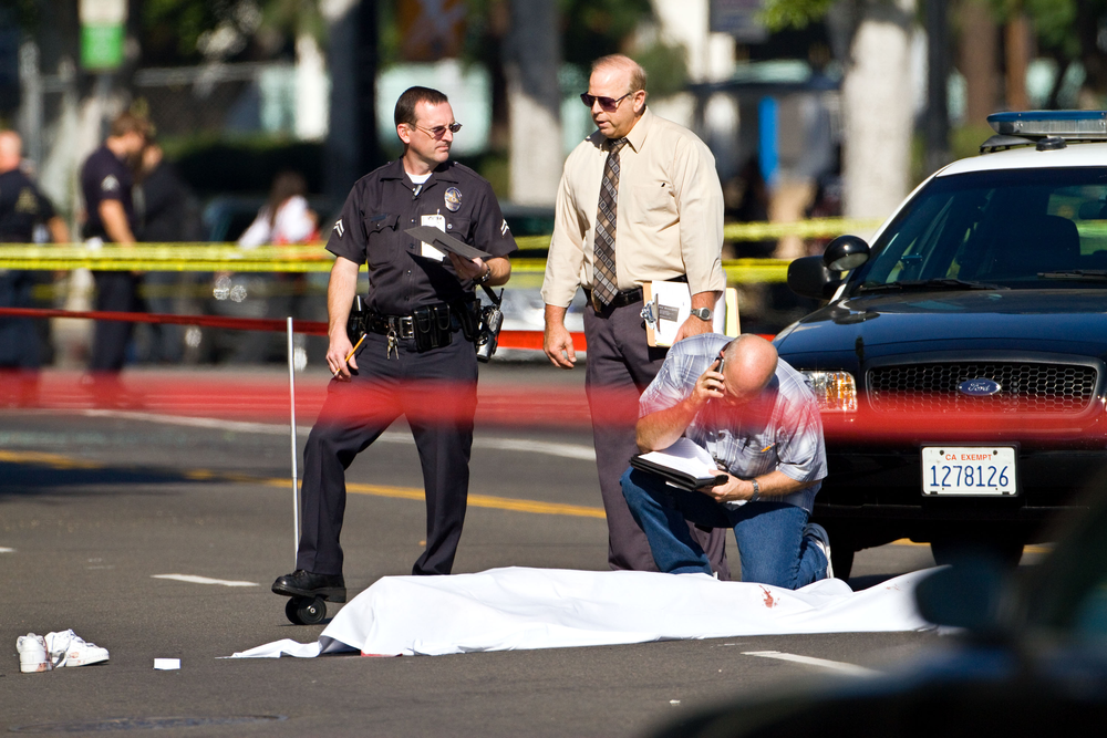 Investigators examine a body at the scene of a fatal shooting, Friday, Dec. 9, 2011, in Hollywood, Calif.
