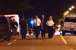 Toronto Police Chief Bill Blair, center, walks down Morningside Ave. in Toronto early Tuesday, July 17, 2012, following a shooting that left at least 19 people injured and two dead at a house party late Monday. The shooting took place after an altercation at an outdoor barbecue.