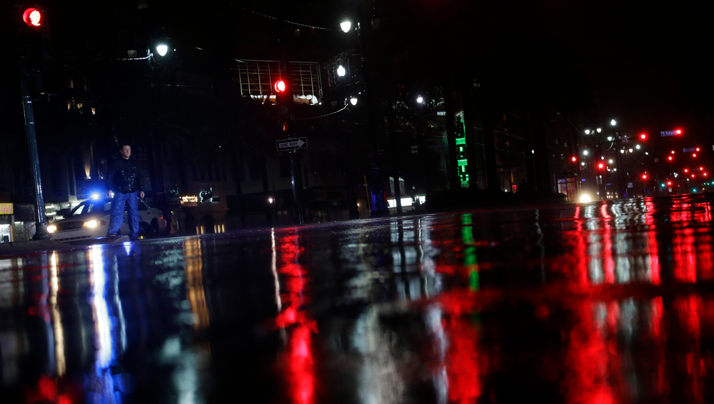 Lights are reflected on Canal Street as a police officer patrolling the area passes a pedestrian as storm bands from Hurricane Isaac hit, Tuesday, Aug. 28, 2012, in New Orleans, Louisiana. Isaac, a massive storm spanning nearly 200 miles from its center, made landfall Tuesday evening near the mouth of the Mississippi River.