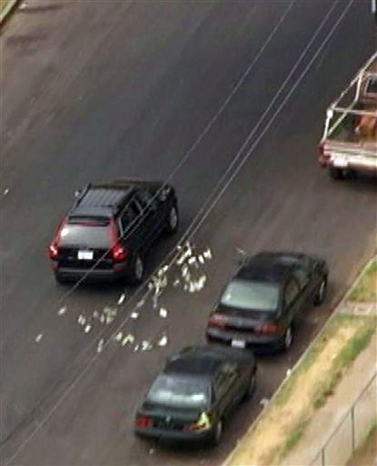 This image provided by KNBC-TV shows bank robbery suspects throwing money from their vehicle during a police pursuit Wednesday Sept. 12, 2012 in Los Angeles. The vehicle was eventually blocked by another vehicle and the suspects were arrested.
