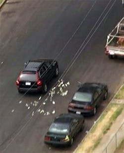 This image provided by KNBC-TV shows bank robbery suspects throwing money from their vehicle during a police pursuit Wednesday Sept. 12, 2012 in Los Angeles. The vehicle was eventually blocked by another vehicle and the suspects were arrested.
