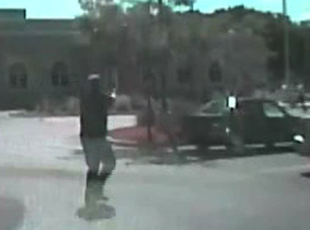 In this image taken from a Aug. 5, 2012 video from Oak Creek Police Lt. Brian Murphy's squad car camera, Lt. Murphy, the first officer on the scene, exchanges fire in the temple parking lot with shooter Wade Michael Page, rear right, as Page emerges from the temple. The video shows Murphy rolling behind a parked car for cover and Page chasing him down, firing multiple shots at him. Milwaukee County District Attorney John Chisholm says Murphy was hit 15 times. Page killed himself following a firefight with Officer Sam Lenda.