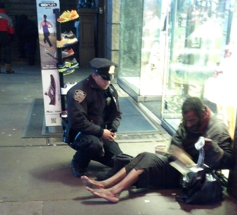 NYPD Officer Larry DePrimo presents a barefoot homeless man in New York's Time Square with boots on Nov. 14.