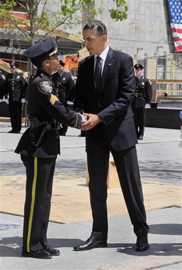 President Barack Obama shakes hands with NYPD Sgt. Stephanie Moses following a moment of silence after he placed a wreath at the World Trade Center site in New York.