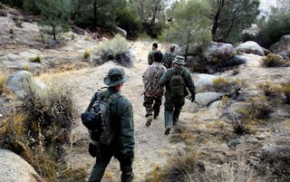 Wardens with the California Department of Fish and Game detain a pair of men during a raid on an illegal marijuana growing operation in the Sierra Nevada foothills.