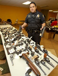 San Diego Police Officer Jonathan Bamba holds a fully automatic tech 9 and a tech 22 at the gun exchange held on Dec. 21.
