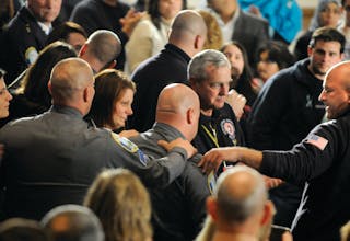 Responders received an emotional standing ovation as they entered the auditorium for a vigil on Newtown, Conn.
