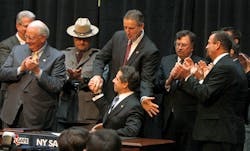New York Gov. Andrew Cuomo, seated at center, gets a congratulatory hand shake from Lt. Gov. Robert Duffy after signing the NY Safe Act on Jan. 16.