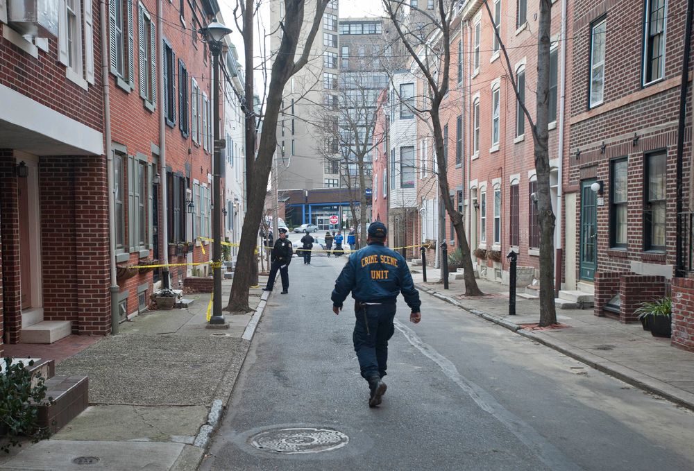 A Philadelphia Police crime scene unit officer walks down street where a woman was found burned to death in her basement in Philadelphia on Jan. 21.
