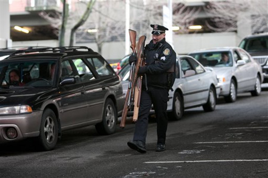 Seattle Police Sgt. Paul Gracy carries guns collected from people in a City of Seattle drive-thru gun exchange program on Jan. 26.