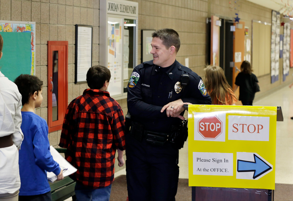 Police Officer Jeff Strack smiles at children changing classrooms at Jordan Elementary School in Jordan, Minn.