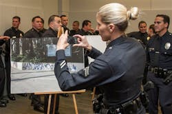 An LAPD Organized Crime Division official takes a photo of an evidence photo showing a gang graffitti by the MS-13 gang on March 13.