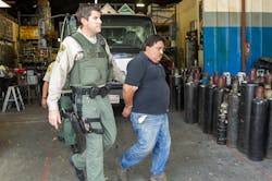 L.A. County Deputy Jim Phillips, left, detains Federico Valencia after a search warrant at Victor Welding Supply, Co. in Los Angeles on March 22.