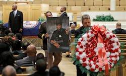 Mourners carry flowers and a photo of of Virginia State Trooper Junius A. Walker, after his funeral at the Good Shepherd Baptist Church in Petersburg, Va. on March 12.