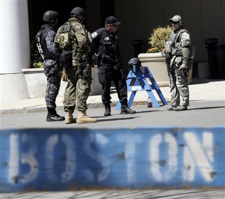 Officials in tactical gear stand guard behind a Boston Police Department barricade near the site of the Boston Marathon explosions on April 17.