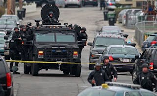 Police in tactical gear arrive on an armored police vehicle as they surround an apartment building while looking for a suspect in the Boston Marathon bombings in Watertown, Mass. on April 19.