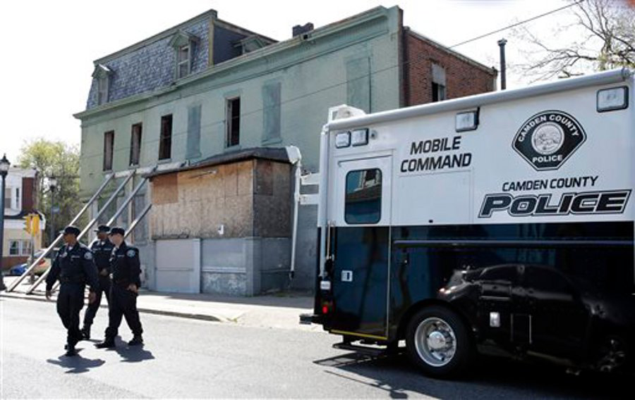 Camden County police officers walk together near a mobile command post as they patrol in Camden, N.J.