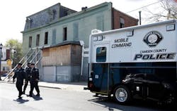 Camden County police officers walk together near a mobile command post as they patrol in Camden, N.J.