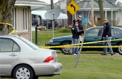 Police officials investigate the scene at a house in Manchester, Ill. on April 24.