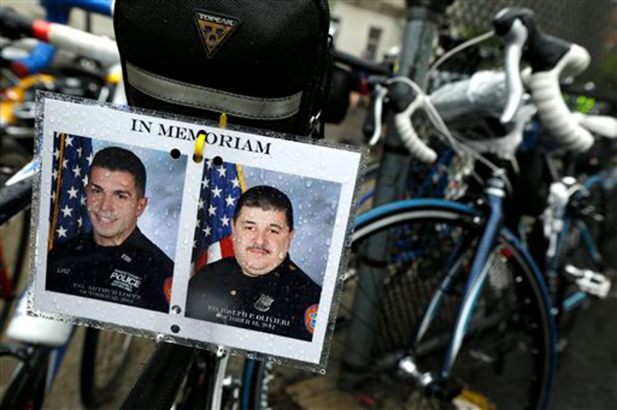 Photos of fallen Nassau County Police Officers Arthur Lopez, left, and Joseph Olivieri -- both killed in the line of duty in separate incidents in October 2012 -- are seen hanging from the seat of a bicycle during a stop along the Police Unity Tour bike ride on May 9. (AP Photo/Julio Cortez)