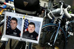 Photos of fallen Nassau County Police Officers Arthur Lopez, left, and Joseph Olivieri -- both killed in the line of duty in separate incidents in October 2012 -- are seen hanging from the seat of a bicycle during a stop along the Police Unity Tour bike ride on May 9. (AP Photo/Julio Cortez)