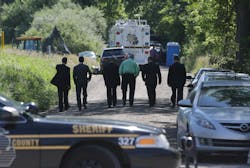 Law enforcement officials walk back to the search area after Robert Foley, special agent in charge of the FBI's Detroit division, addressed the media in Oakland Township, Mich. on June 19. Law enforcement officials walk back to the search area after Robert Foley, special agent in charge of the FBI's Detroit division, addressed the media in Oakland Township, Mich. on June 19.