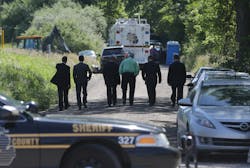 Law enforcement officials walk back to the search area after Robert Foley, special agent in charge of the FBI&apos;s Detroit division, addressed the media in Oakland Township, Mich. on June 19.
