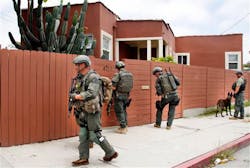Los Angeles Sheriff&apos;s deputies search a city street for suspects after two police officers were shot and wounded in an attack outside a police station in the Mid-City area of Los Angeles on June 25.