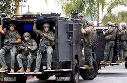 Los Angeles Sheriff&apos;s deputies search a city street for suspects after two police officers were shot and wounded in an attack outside a police station in the Mid-City area on June 25.