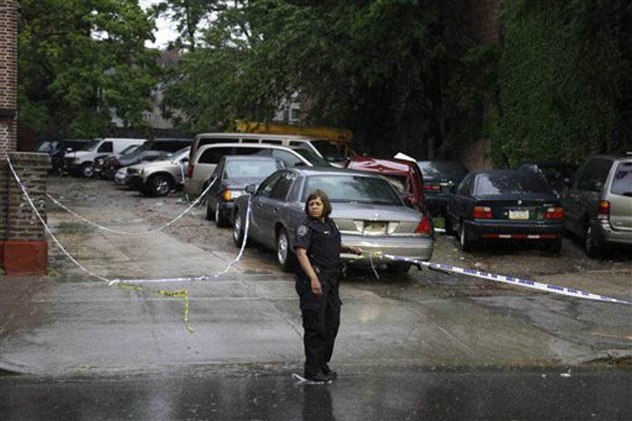 An NYPD police officer holds crime scene tape near a crime scene where three people were shot over the weekend in Brooklyn on June 3.
