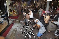 Rioters celebrate, loot and steal a bike after smashing a stop sign through the windows of Easyrider business on the corner of Main and Orange Streets downtown Main Street in Huntington Beach, Calif. on July 28. Rioters celebrate, loot and steal a bike after smashing a stop sign through the windows of Easyrider business on the corner of Main and Orange Streets downtown Main Street in Huntington Beach, Calif. on July 28.