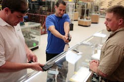 Sales associate Nick Ambroziak, right, assists Steven Beard, left, and Andy Spentzos with guns on July 9 at Gat Guns in East Dundee, Ill.