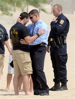 Ocean City Detective Carl Perry, right center, consoles Officer Matt MacFarlane, left, on the beach in Ocean City, Md. on July 1 after a plane crash Sunday that killed police officers.
