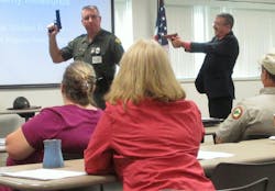John L. Fernatt, right, of West Virginia&apos;s Bureau of Risk and Insurance Management surprises Sgt. Michael Lynch of the state police, left, with a fake weapon during a workshop for civilian office workers on how to survive a mass shooting in the workplace on May 30, in Charleston, W.Va.