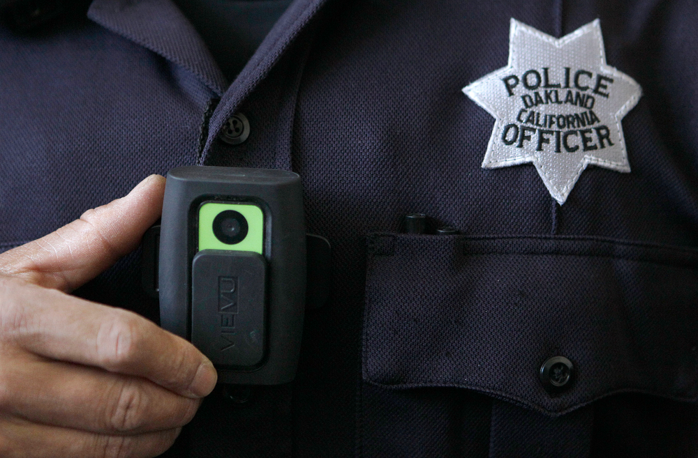 Officer Huy Nguyen shows a video camera worn by some officers in Oakland, Calif.