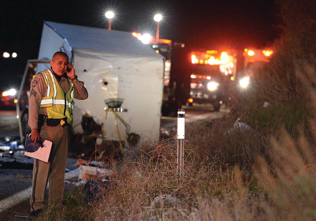 A California Highway Patrol officer stands in front of an overturned trailer after a crash that resulted in eight fatalities.